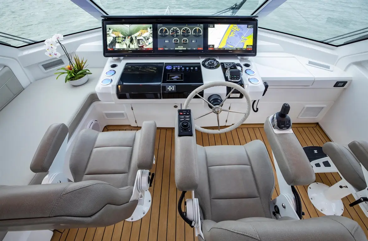 Luxury yacht control panel featuring dual screens, stylish seating, navigation controls, and a serene aquatic backdrop.